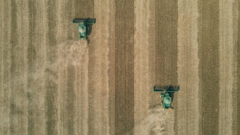 Drone captures two harvesters working in sprawling soybean fields in Brazil.